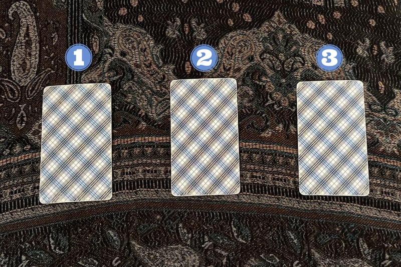 Tres cartas del Tarot ocultas sobre una tela.